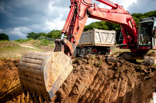 Industrial excavator digging a hole and loading earth in a dumper truck at a quarry or a construction site — Stock Image Industrial excavator digging a hole and loading earth in a dumper truck at a quarry or a construction site Royalty Free Stock Images