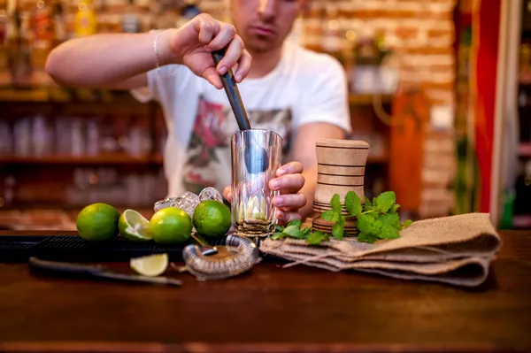 Μπάρμαν προετοιμασία mojito cocktail ποτό, με ασβέστες, πάγο και μαύρη ζάχαρη — Φωτογραφία Αρχείου