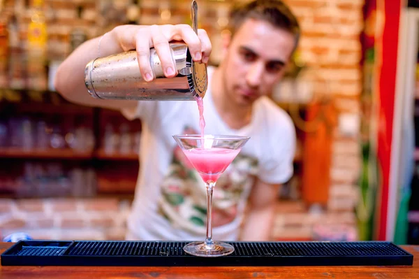 Bartender preparar e derramar coquetel alcoólico cosmopolita — Fotografia de Stock