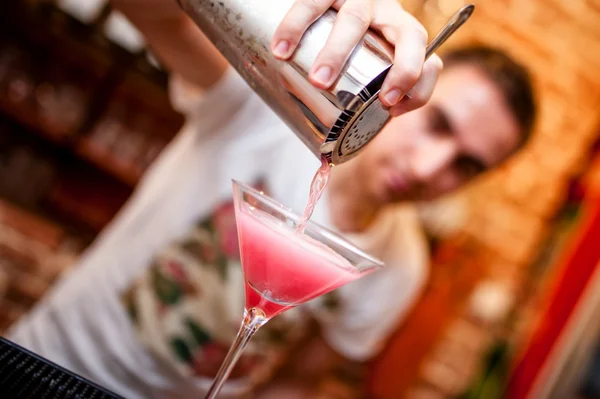 Barman prépare et verse une boisson alcoolisée cosmopolite au bar. Boisson alcoolisée avec vodka, triple sec, jus de canneberge et jus de citron — Photo