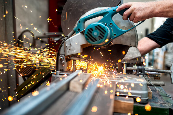 Industrial worker using a  compound mitre saw with circular blade for cutting metal and plastic