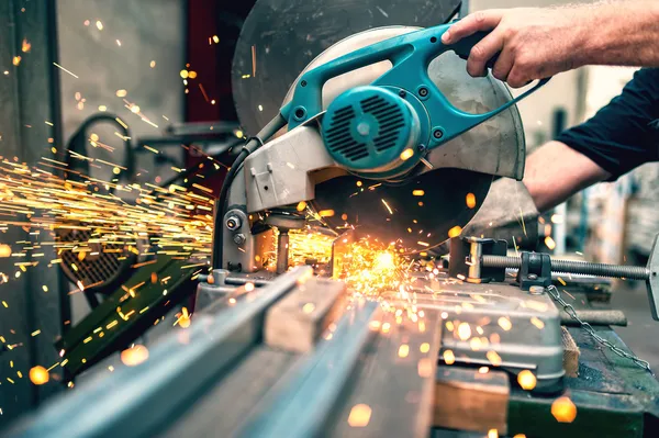 Trabajador industrial que utiliza una sierra de mitra compuesta con hoja circular para cortar metal y plástico — Foto de Stock