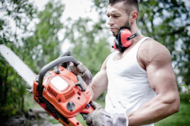 kızgın kaslı erkek oduncu, el, bir chainsaw ile woodworker portresi poz