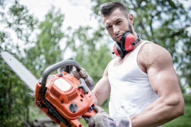 agresif kaslı erkek oduncu, el, bir chainsaw ile woodworker portresi poz
