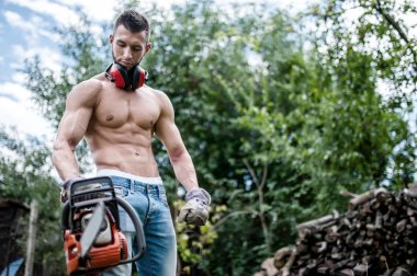 Testere ve koruyucu dişli kesme kereste için hazır olan seksi adam portresi