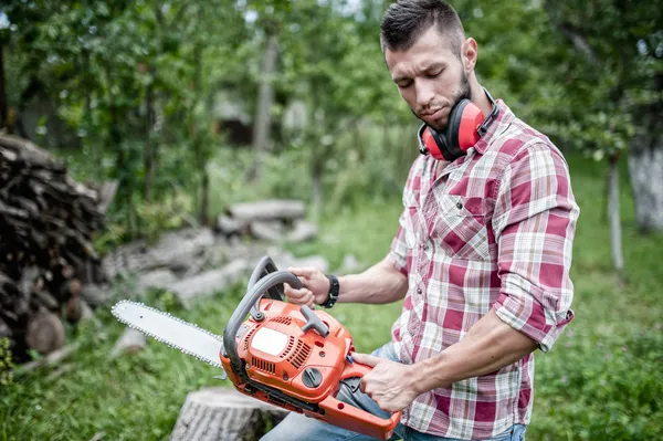 Portrait of sexy and handsome man with chainsaw and protective gear ready for cutting wood — Stock Photo, Image