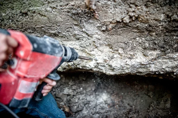 Uomo con attrezzo di perforazione e macchinari professionali distruggendo un muro di cemento sotterraneo — Foto Stock