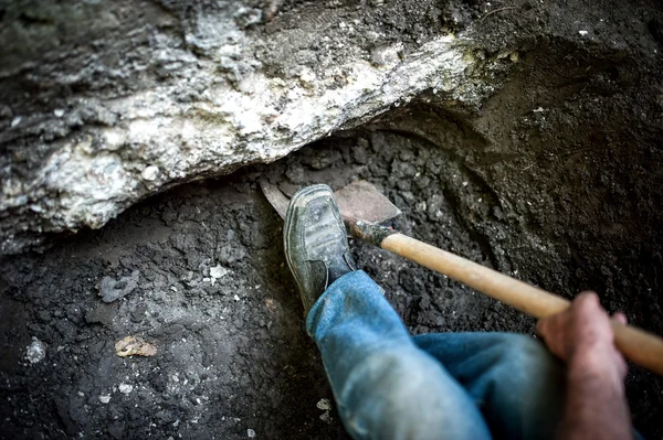 铁铲在地上的一个洞工作的人 — 图库照片