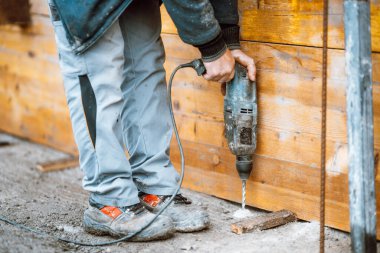 details of construction works - worker on construction site using drilling machine, bricklaying and boring details