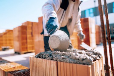 industrial bricklayer installing bricks on construction site using mortar and trowel