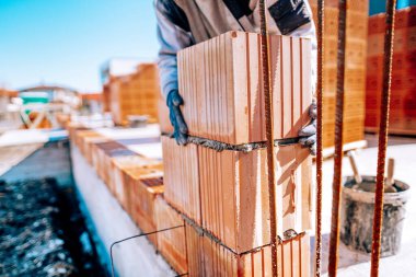 Close up of industrial bricklayer worker installing bricks on construction site