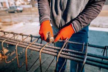 construction worker - hands securing steel bars with wire rod for reinforcement of concrete