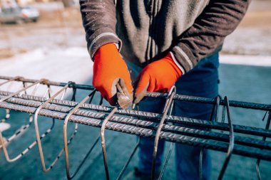Male construction worker - hands securing steel bars with wire rod for reinforcement of concrete