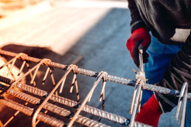 people details of construction worker hands securing steel bars with wire rod for reinforcement of concrete