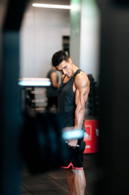 Vücut geliştirici beden eğitimi, antreman ve dambıl kullanıyor.