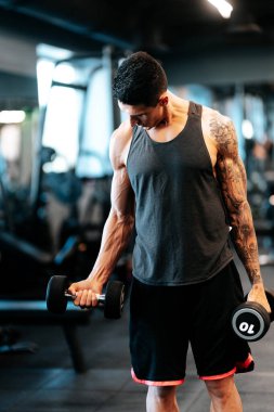 Spor salonunda egzersiz yapan bir adam, spor salonunun mankafalarıyla çalışan sağlıklı yaşam konsepti.