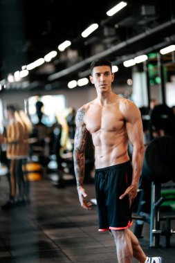 Spor salonundaki eğitimden sonra poz veren yakışıklı adam. Spor yapan ve egzersiz yapan spor eğitmeni ve sporcunun detayları