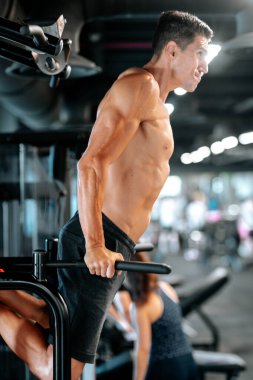 Spor salonunda spor yaparken kaslı genç bir adam, triseps egzersizi.