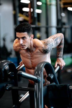 Spor salonunda triseps egzersizi yapan sağlıklı bir fitness adamı. Yakışıklı, profesyonel sporcu spor salonunda çalışıyor, yarışmaya hazırlanıyor.