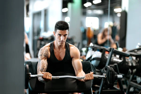 フィットネスジムで運動する筋肉トレーナー ジムでバーベルと仕事をしてる男 — ストック写真