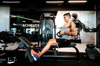 Spor salonunda çalışan profesyonel bir sporcunun portresi, barfiks çekmek ve sırt antrenmanı yapmak. Spor salonunda kaslı bir adam ağırlık kaldırıyor.