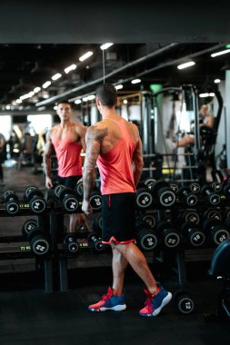 Kas kaslı atletik bir adamın portresi. Kol ve kol kaslarını çalıştırıyor, spor salonunda ağırlık kaldırıyor. Sporcu ve profesyonel antrenör, spor salonunda ağırlık çalışıyor.. 