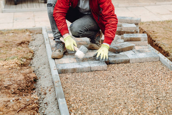 Укладка плит из серого бетона во внутреннем дворе дома на фундаменте из гравия.