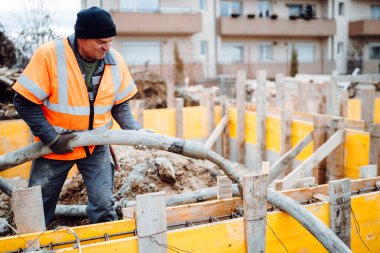 Beton pompayla beton döken işçiler. İnşaat alanının ayrıntıları ve işçilerin iş kıyafetlerinin ayrıntıları