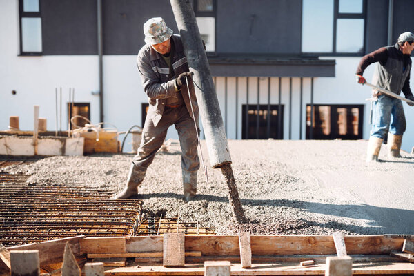 Construction worker working on building a house and pouring cement into beams