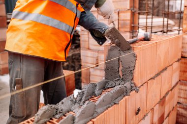 Yeni bir ev inşaatı, tuğla duvar inşaatı mala, çimento ve harçla. Profesyonel inşaat işçisi çalışıyor.