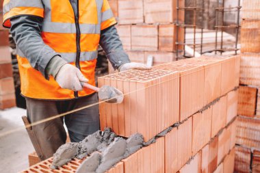 Yeni bir ev inşaatı, tuğla duvar inşaatı mala, çimento ve harçla. Profesyonel inşaat işçisi çalışıyor.