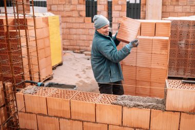 Duvarlar inşa eden mutlu inşaat işçisinin portresi, duvarcı evi, şantiyede çalışan beyaz erkek.