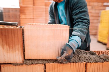 Tuğla döşeyen işçilerin detayları, macun bıçağı, spatula ve tuğla havan topu. Ev inşaatı detayları
