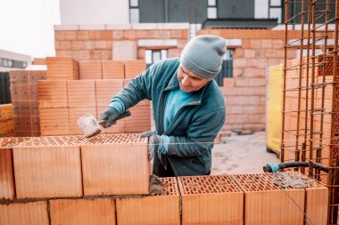 Tuğla döşeyen işçilerin detayları, macun bıçağı, plastik çekiç ve tuğla havan topu. Ev inşaatı detayları