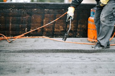 İnşaat işçileri, çatı ustaları yeni evin su geçirmez hale getirilmesi için su geçirmez zar döşüyorlar. Ev su geçirmez ve yalıtımlı