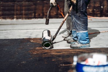 İnşaat işçileri pürmüz ve gaz kullanarak zarı su geçirmez yalıtım sistemi kuruyorlar.