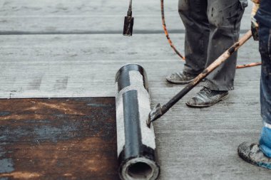 İnşaat işçileri pürmüz ve gaz kullanarak zarı su geçirmez yalıtım sistemi kuruyorlar.