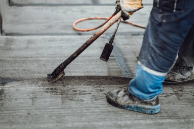 İnşaat işçileri çatıyı zift zarı ile yalıtıyorlar. İnşaat alanında su geçirmez detaylar. Bituminous membranlı su geçirmez sistem detayları ve çatıya kurulumu.