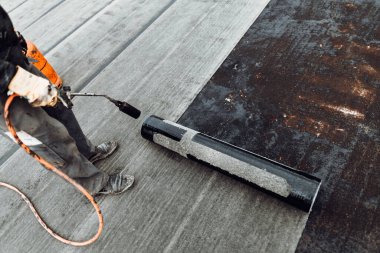 İnşaat işçileri, çatı ustaları yeni evin su geçirmez hale getirilmesi için su geçirmez zar döşüyorlar. Ev su yalıtımı ve yalıtımı