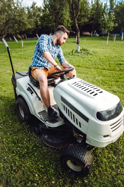 芝生トラクターを使用した庭師労働者と庭を通して草を切断 — ストック写真