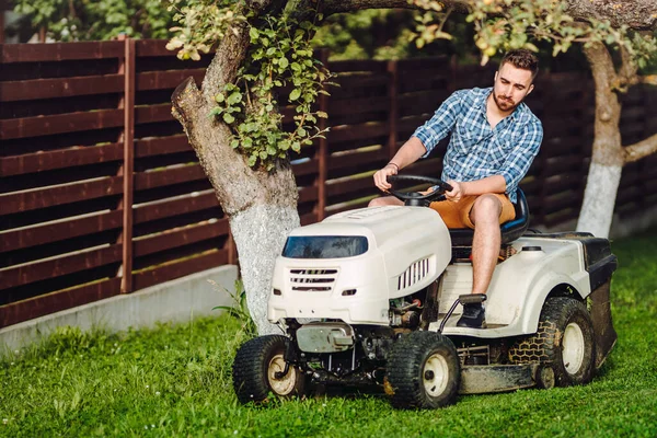 Professional gardener and lawn mower cuts the grass using tracto