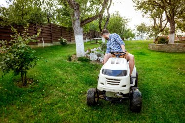 Profesyonel bahçıvan bahçe düzenlemesi yapıyor. Bahçede traktör kullanıyor..