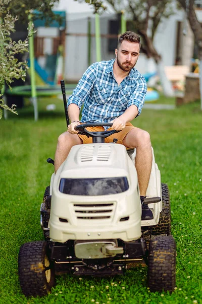 Gardening details with worker using lawn tractor