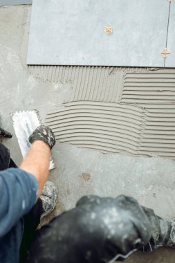 İnşaat ve yenileme işleri. Seramik fayans işçisinin fayansları yapıştırıcıya yerleştirme detayları