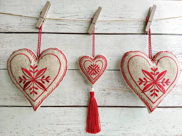 Drie hartwanden opgehangen aan linnen met rood borduurwerk en kwastje — Stockfoto