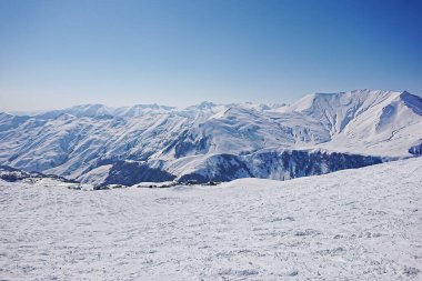 Görkemli karlı zirveler ve güneş ışınlarında mavi gökyüzü