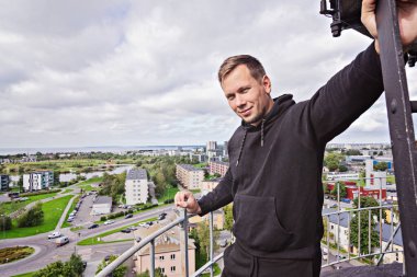 Milenyum erkeği kameraya bakarak şehir manzarasının tadını çıkarıyor. Seyahat tutkusu konsepti