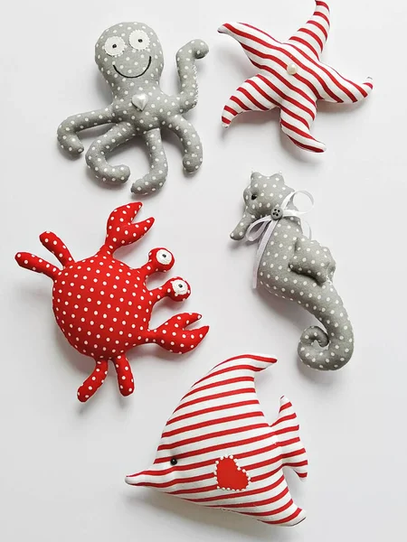 Handmade cartoon stuffed toys in hand, sea life octopus, crab, fish and seahorse. Toy crab, octopus, starfish, seahorse, and fish. DIY Flat lay