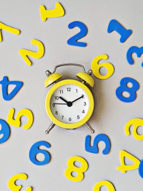 Nihai gri zemin üzerinde sarı alarm saati, mavi ve sarı sayılar düz yatıyordu. Okul konseptine dönelim.