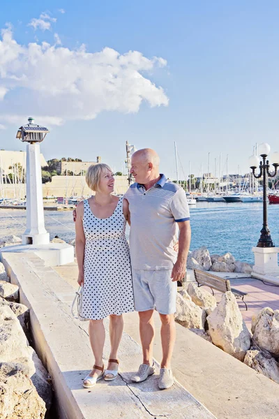 Middle-aged couple of baby boomers people posing for photograph opposite blue sea on sunny summer day. Travel boom after end of coronavirus concept